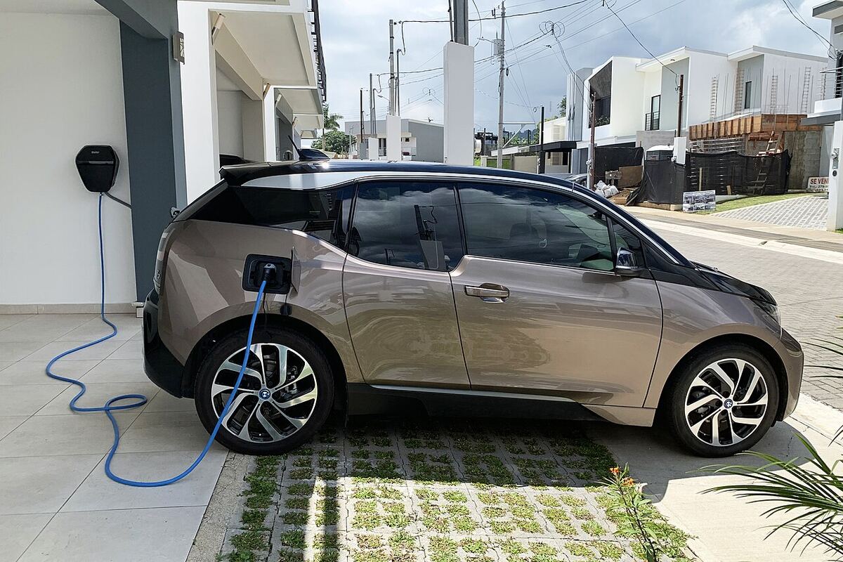 Voiture électrique en charge sur une borne murale devant une maison